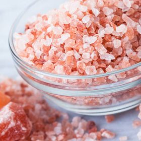 Natural light photo of bowl of Himalayan Pink Salt in with small and large chunks. Selective focus on top of salt in bowl